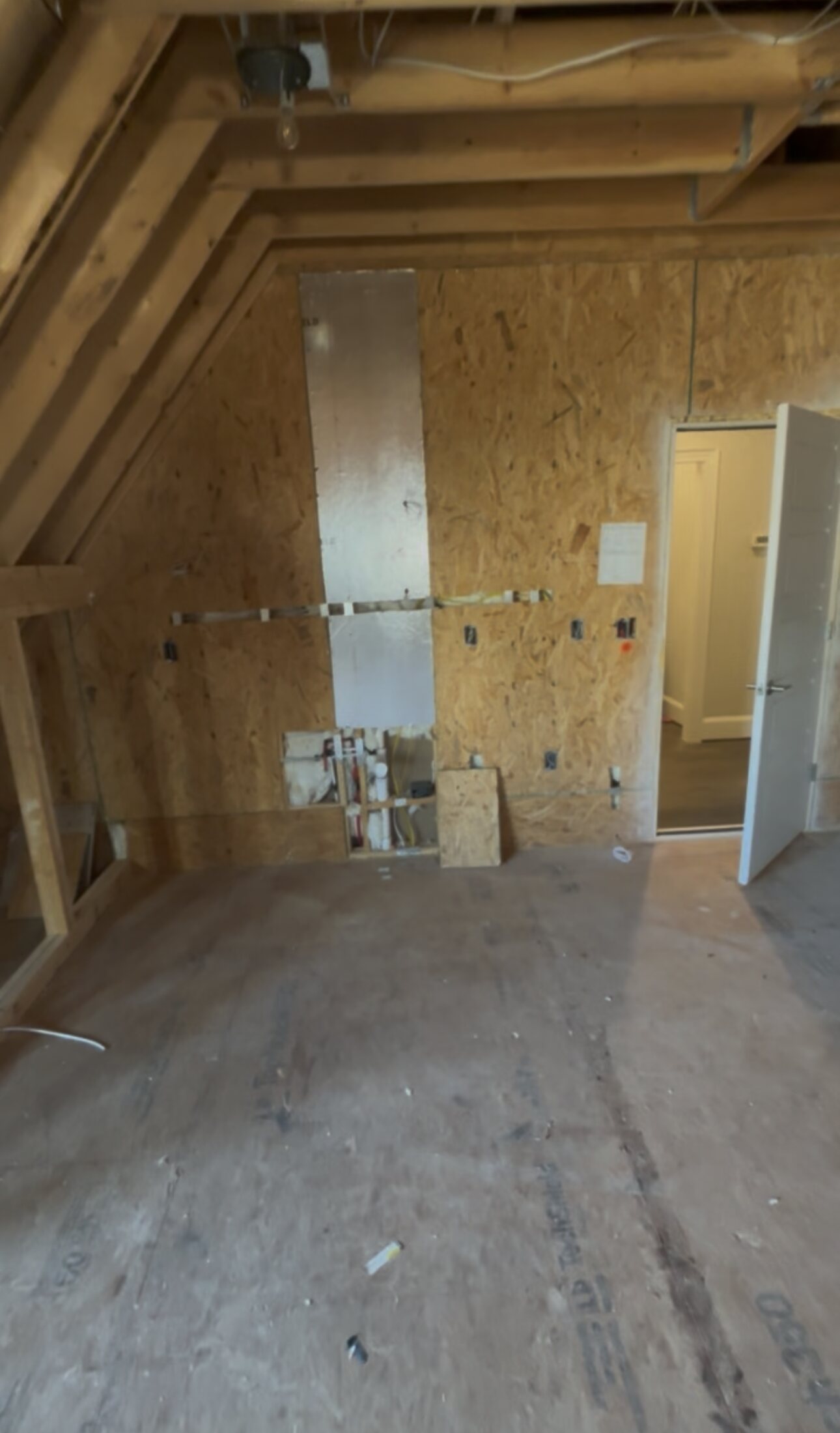 Bare stud walls and sheathing in the unfinished bonus room