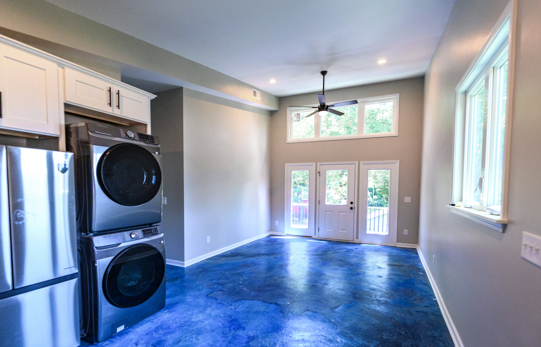 Open living area with stained concrete floors and french doors to a balcony