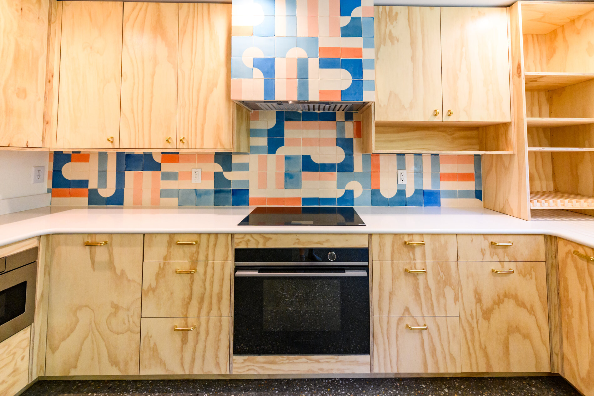 Finished custom kitchen with plywood cabinetry and a graphic tile backsplash